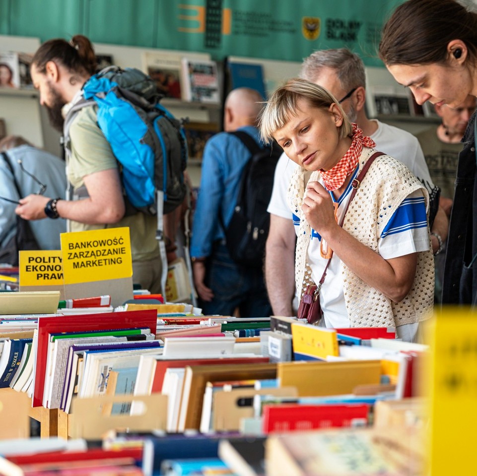 osoby szukają ksiażek w trakcie giełdy. książki leżą na stołach.