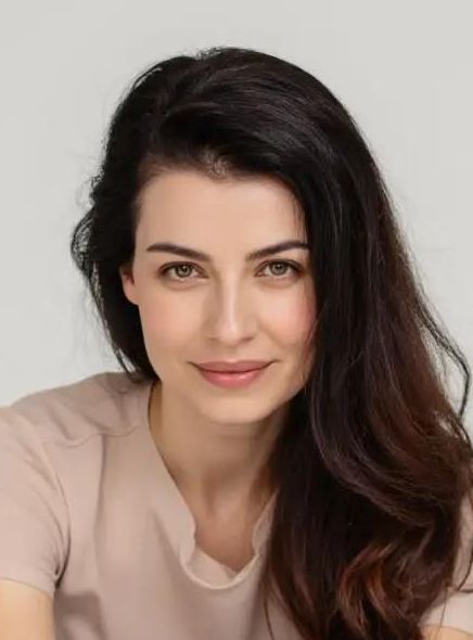 Irena Kwaśniewska, portret kobiety, ma ciemne rozpuszczone włosy, łagodny uśmiech., 
