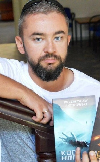 mezczyzna w bialej koszulce, trzyma swoją książkę. 