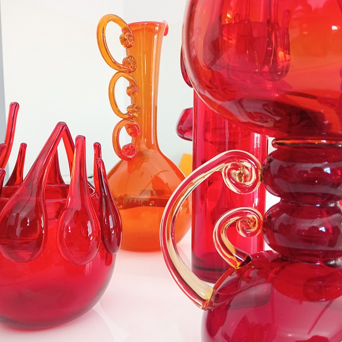 Fot. Barbara Banaś / zdjęcie dokumentujące i promujące wystawę "Szklane życiorysy" w MN we Wrocławiu, zdjęcie przedstawia czerwone i pomarańczowe szklane wazony-naczynia, dzieła sztuki