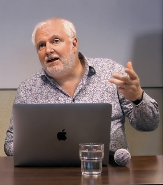 Radu Tukan, mężczyzna przed komputerem przemawia do widowni. 