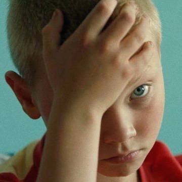 blond chłopczyk z rączką na głowie opartą