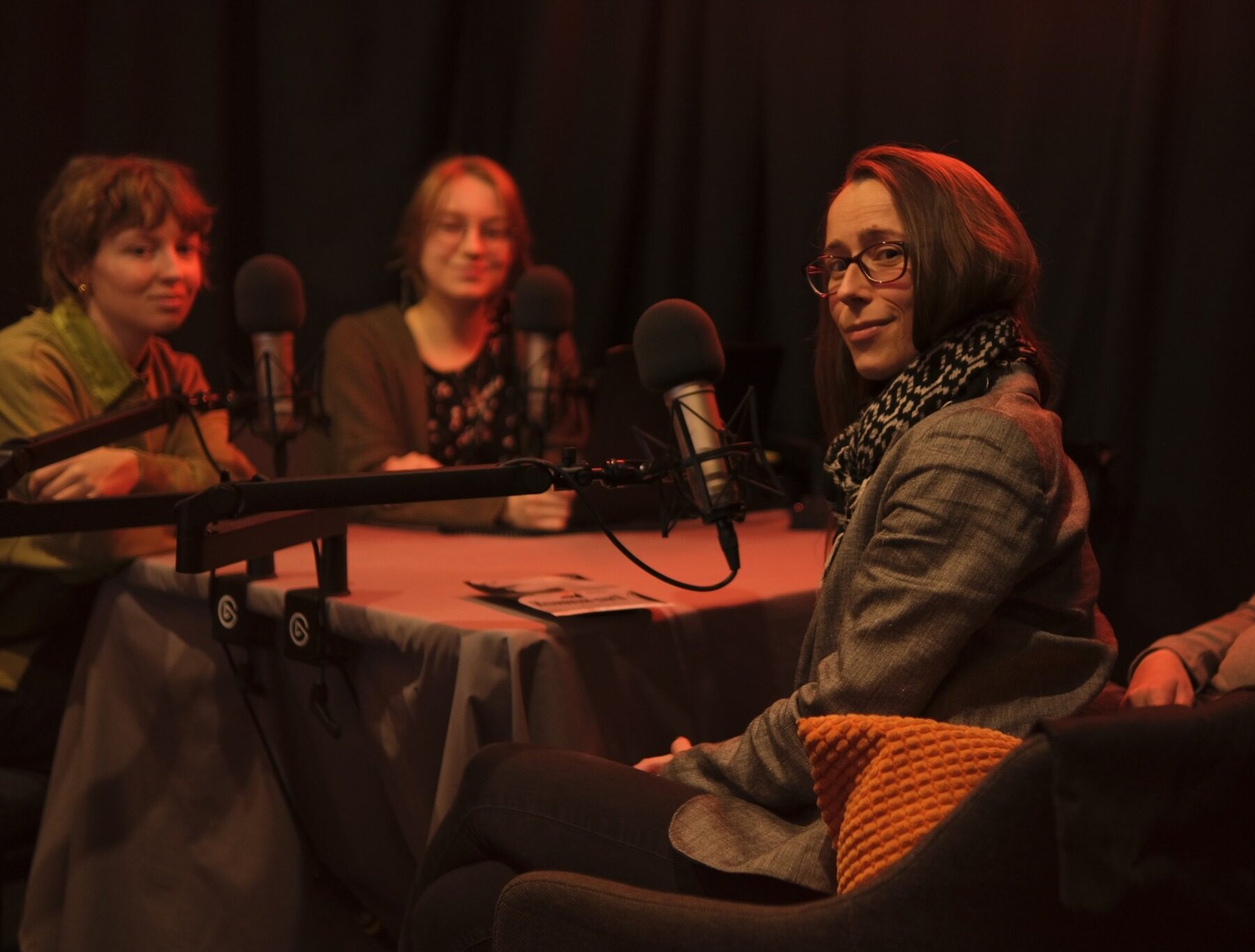 cztery osoby w studio radiowym, ciemno, lekkie czerwone swiatło