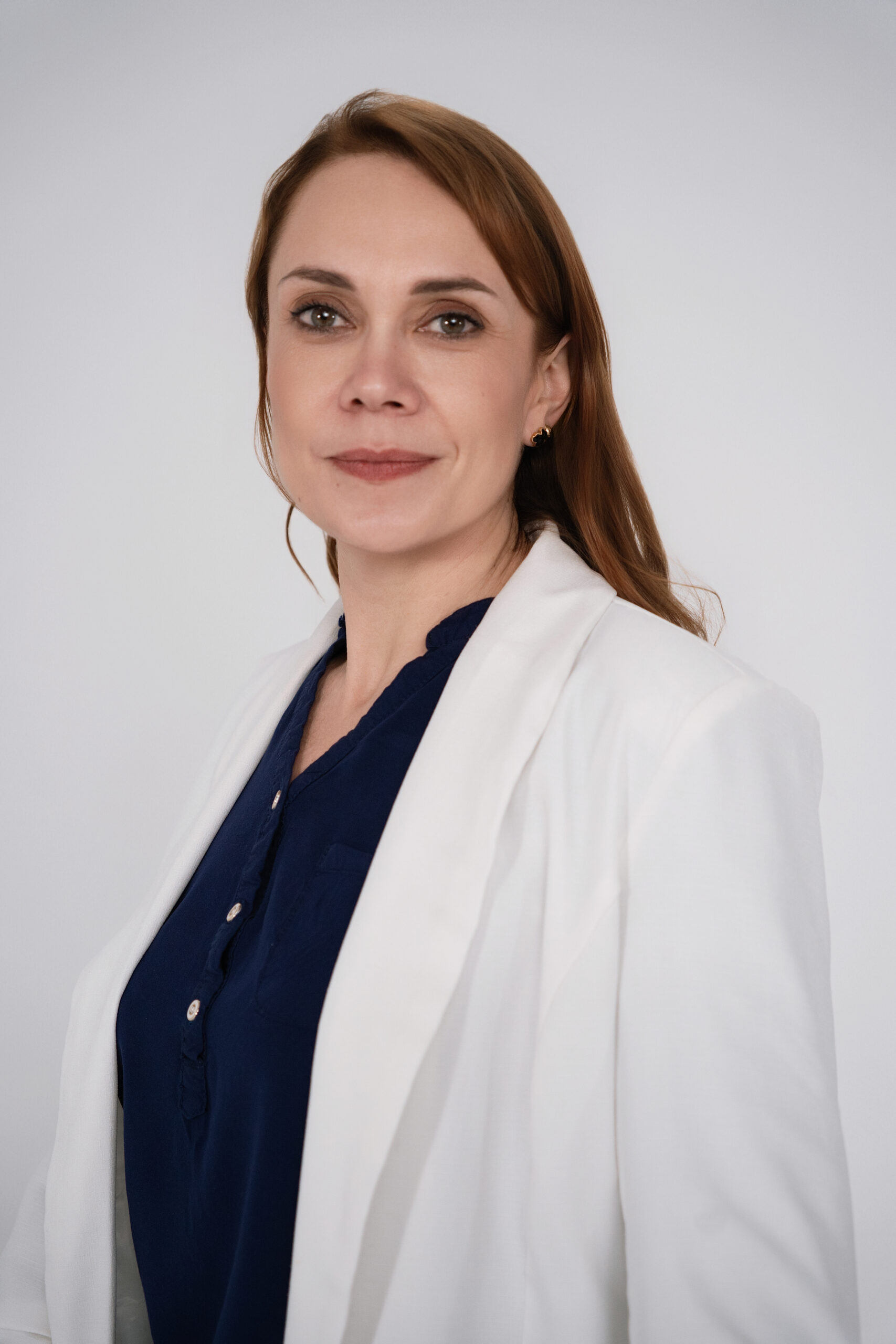 Portret kobiety z lekkim uśmiechem na jasnym tle.
