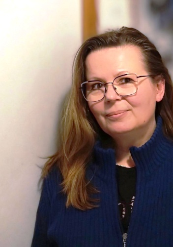 kobieta w ciemnoniebieskiej koszuli, w okularach, lekko się uśmiecha, półprofil